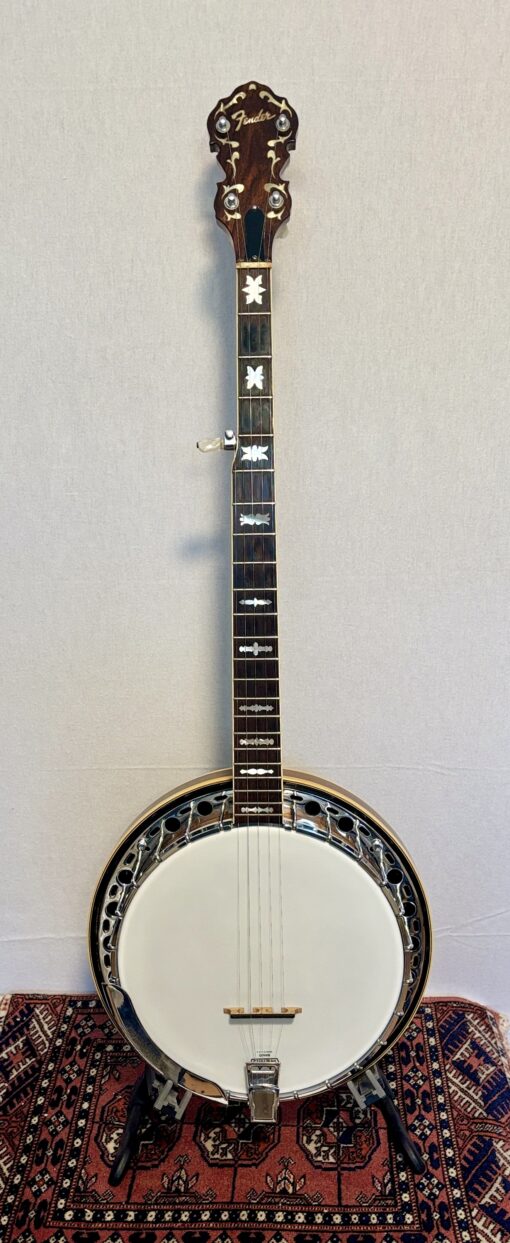 Full front view of a 1960s Fender Artist banjo with walnut resonator and cream binding on a stand