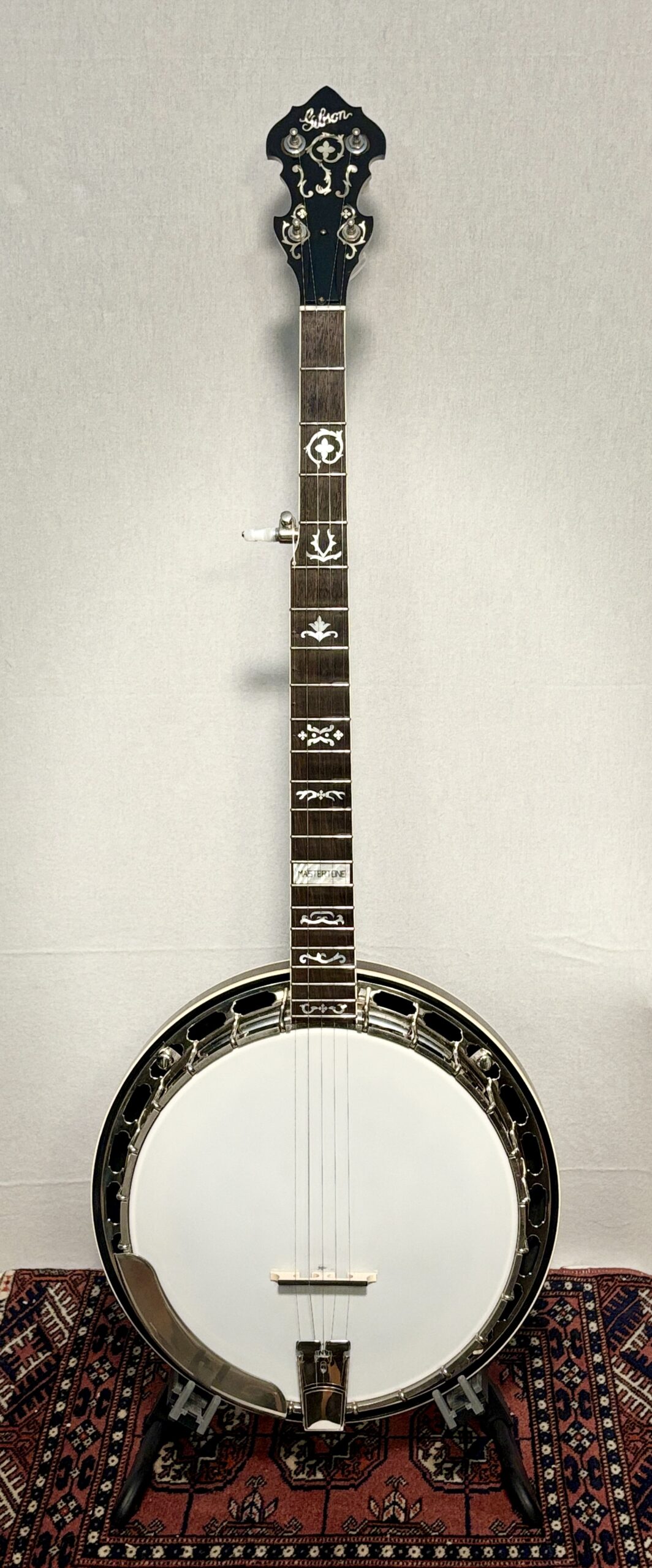 2005 Gibson RB-3 5-string banjo with wreath inlay pattern displayed on stand, showing full instrument with white head, rosewood fretboard, nickel hardware, and ornate pearl inlays