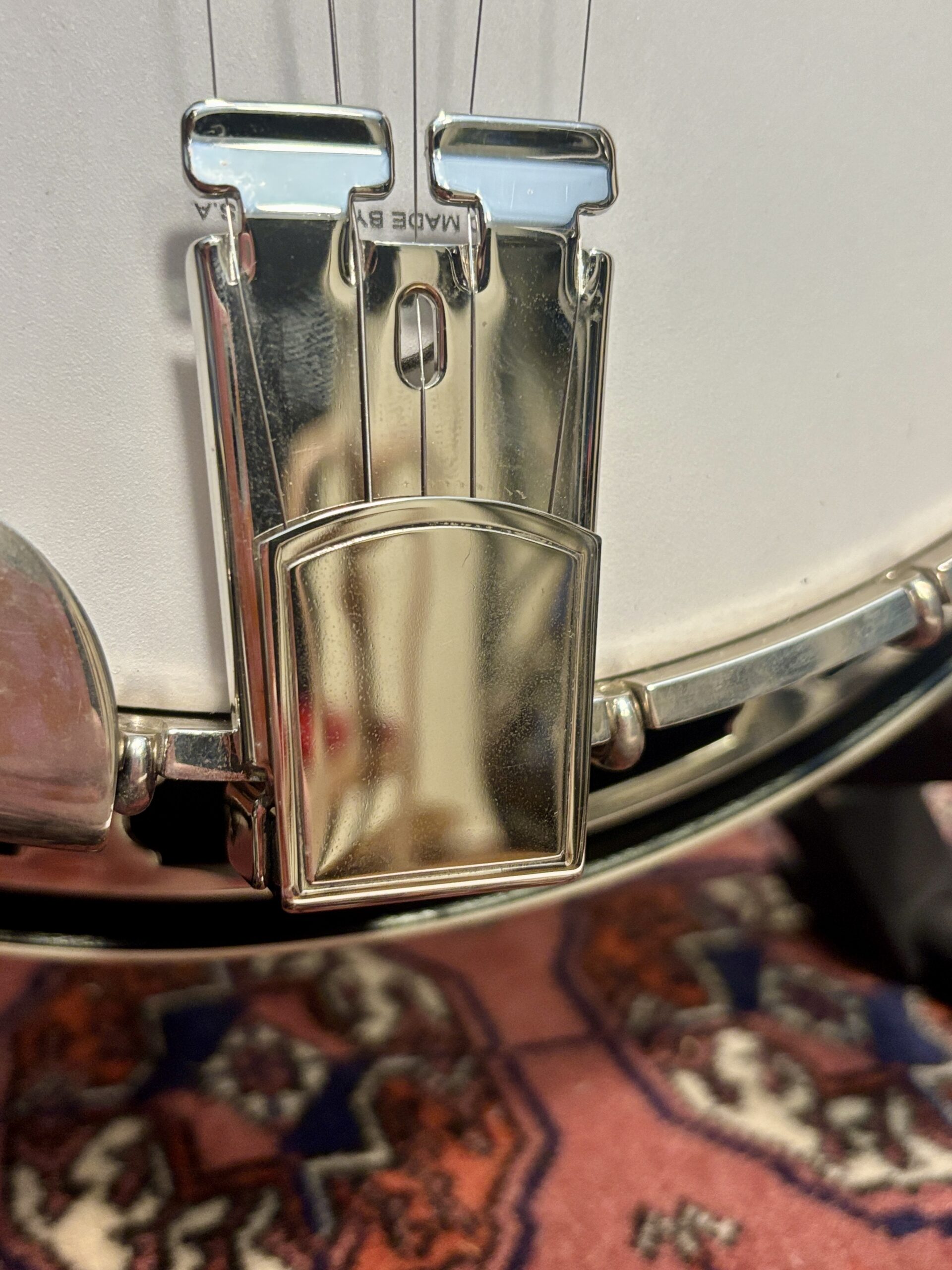 Gibson banjo tailpiece showing mounted on white frosted head
