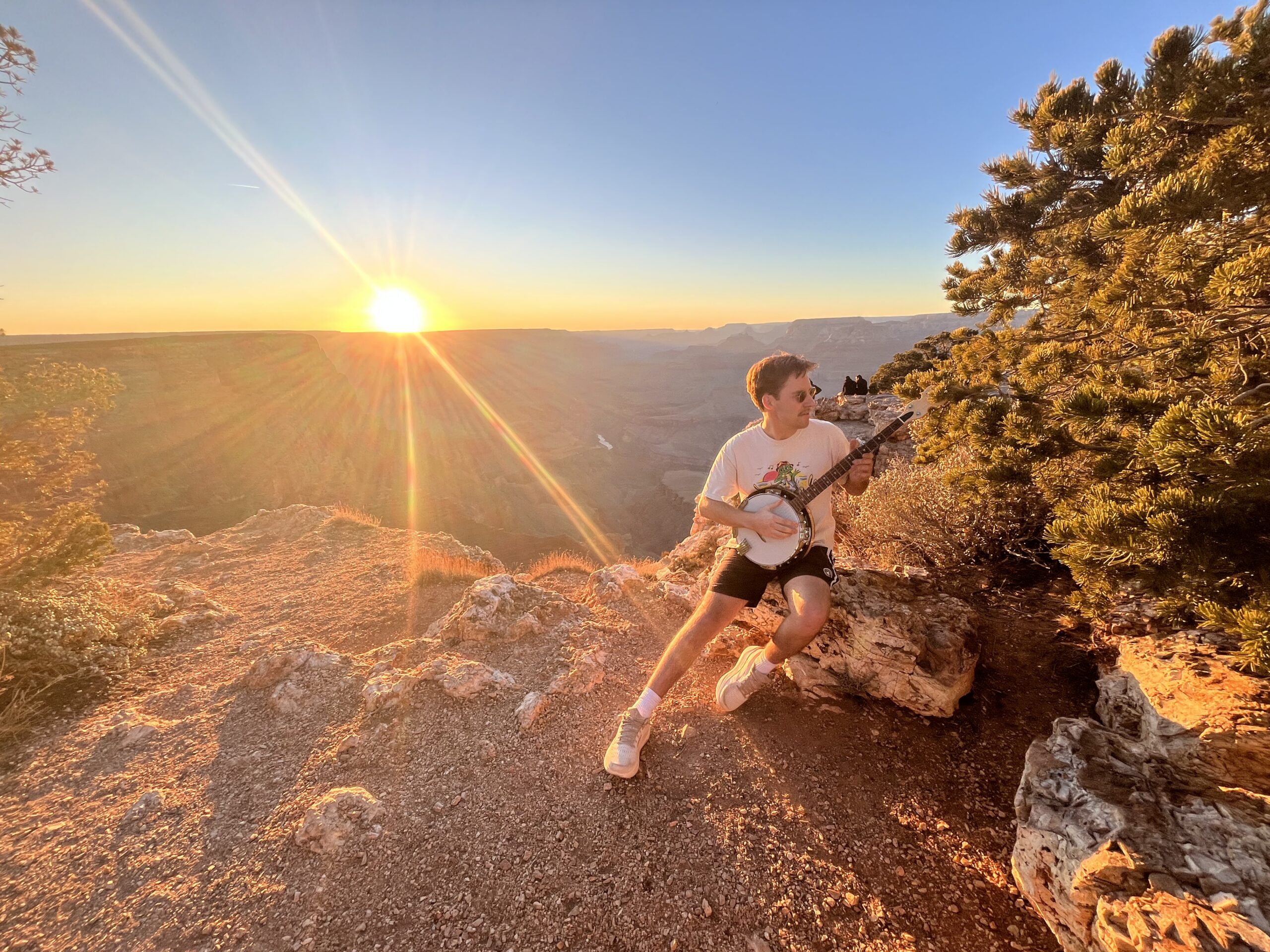 Gold Tone CC-100R banjo leaning against canyon wall at Grand Canyon with orange post-sunset sky and Colorado River visible below