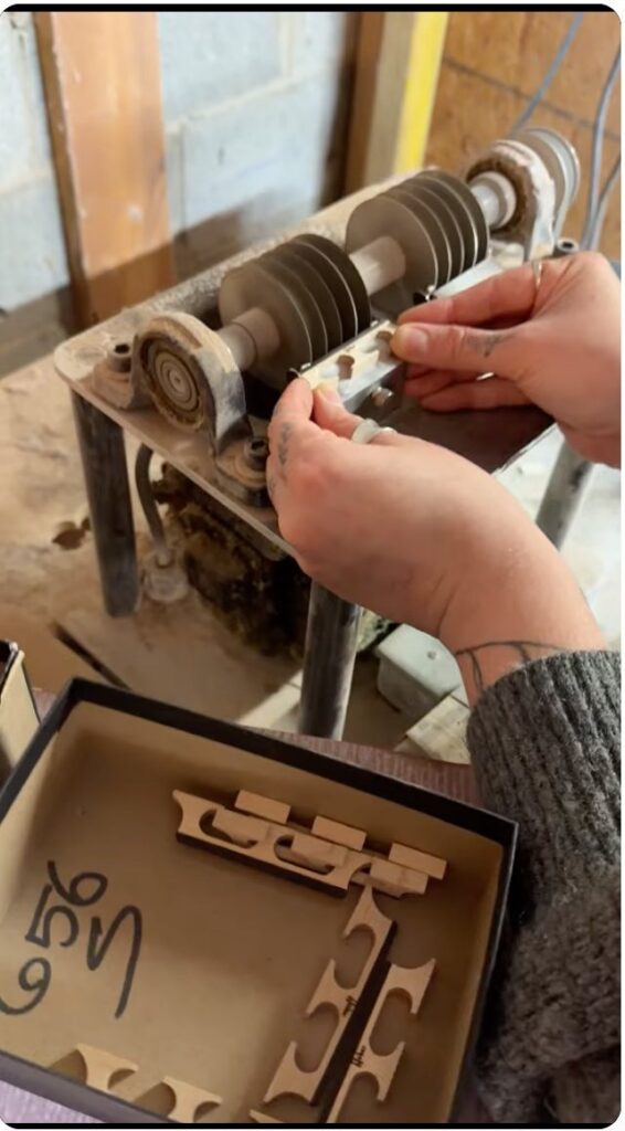 Banjo Warehouse banjo tech Tara Buchy notching Huber maple and ebony banjo bridges at the Huber Banjo factory in Hendersonville, Tennessee