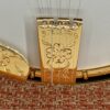 Close-up of the gold-plated, hand-engraved Stelling tailpiece on the 1987 Stelling One-Bird Virginian, showing the Stelling name in script above a Dogwood blossom motif. A corner of the engraved armrest is visible at left.