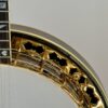 Upper-rim detail of the 1987 Stelling One-Bird Virginian, showing the gold-plated flange with the signature Dogwood-shaped cutouts, the engraved tension hoop, and the walnut rim binding.