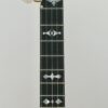 Close detail of the Huber Truetone Custom 625-13 engraved gold-plated tailpiece holding the strings above the white head Close detail of the engraved gold tailpiece on the Huber Truetone Custom 625-13.