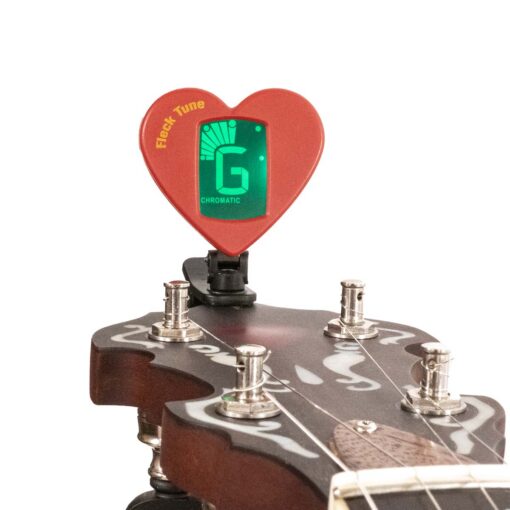 Gold Tone Fleck Tune clip-on tuner, red heart-shaped body clipped to a banjo headstock with the green display reading G in chromatic mode