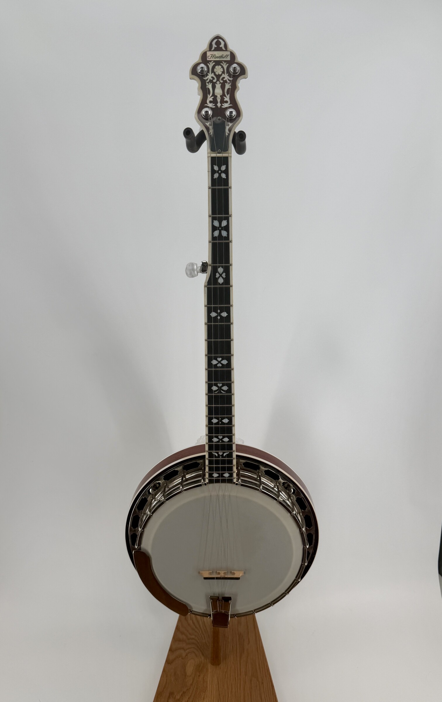 2010 Flint Hill FHB-280A banjo with a full front view of the inlaid peghead, bound fingerboard and pot on a display stand, at Banjo Warehouse in Yellow Springs, Ohio.