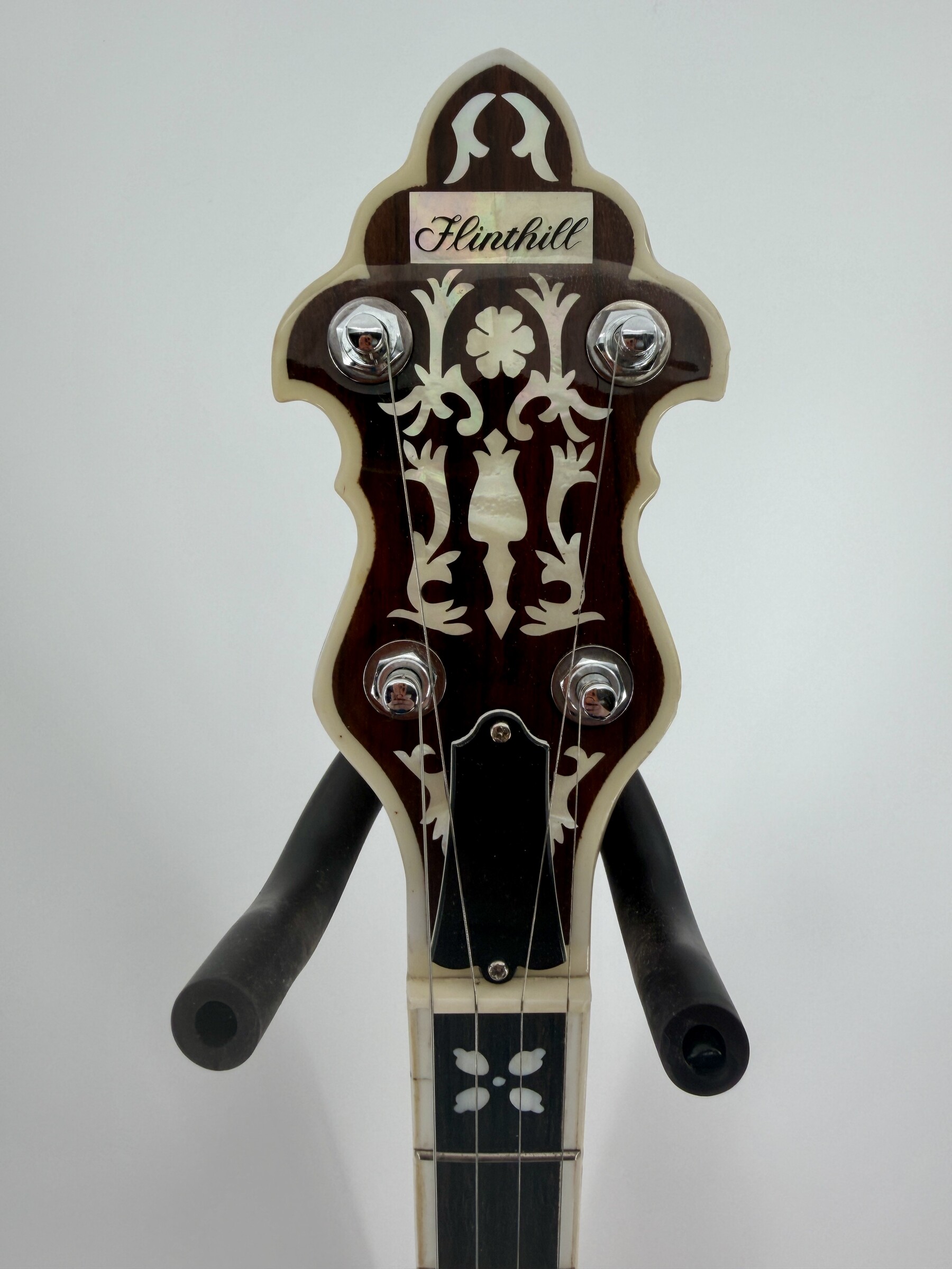2010 Flint Hill FHB-280A banjo with the Flint Hill peghead, its decorative pearl-look inlay and four tuners, at Banjo Warehouse in Yellow Springs, Ohio.